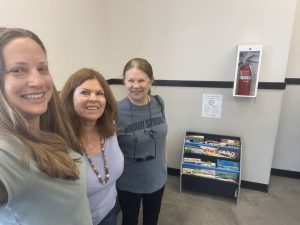 Kati, Liz and Sandi showing the stocked bookshelf