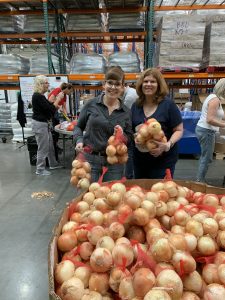 Meg and Liz dropping their bags of onions into the container